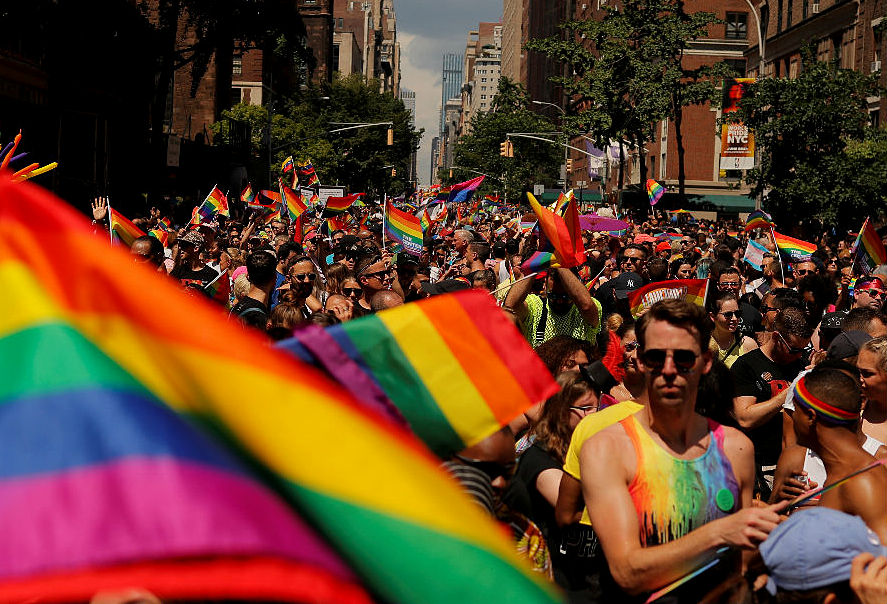 A picture of LGBTQIA members holding flags on the road